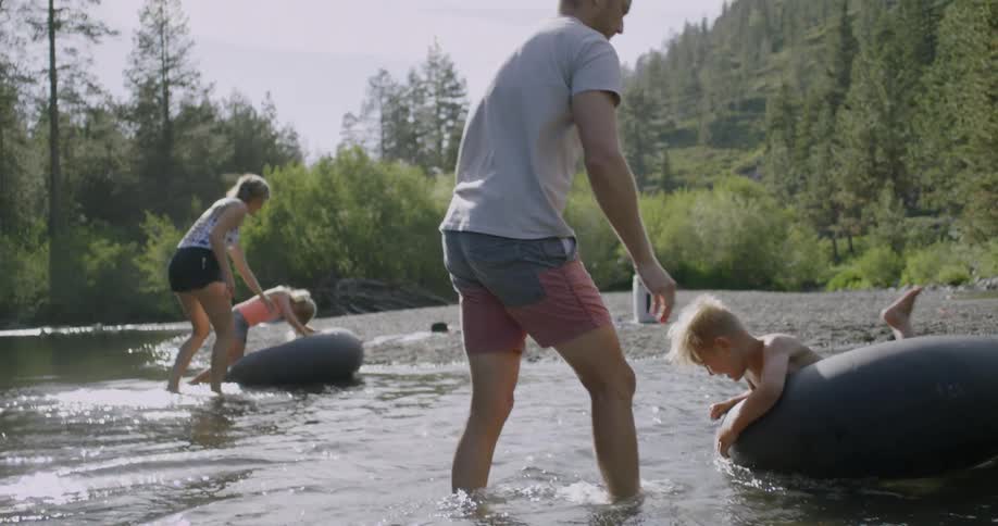 Some kids are sitting in some tube floaties being watched by their parents