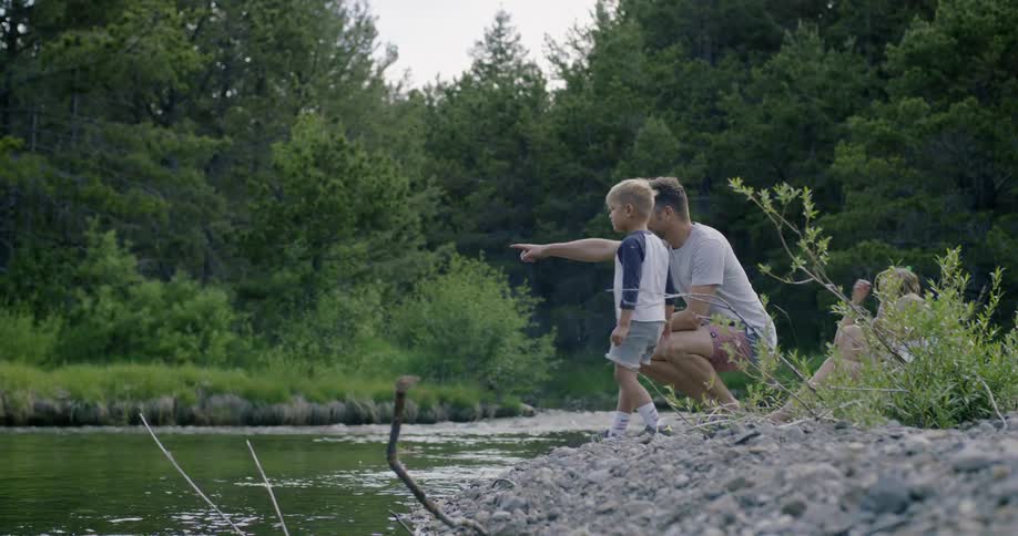 Family playing next to and throwing rocks in river