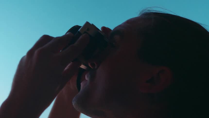 Man taking pictures at the mouth of a cave near a beach on a clear day