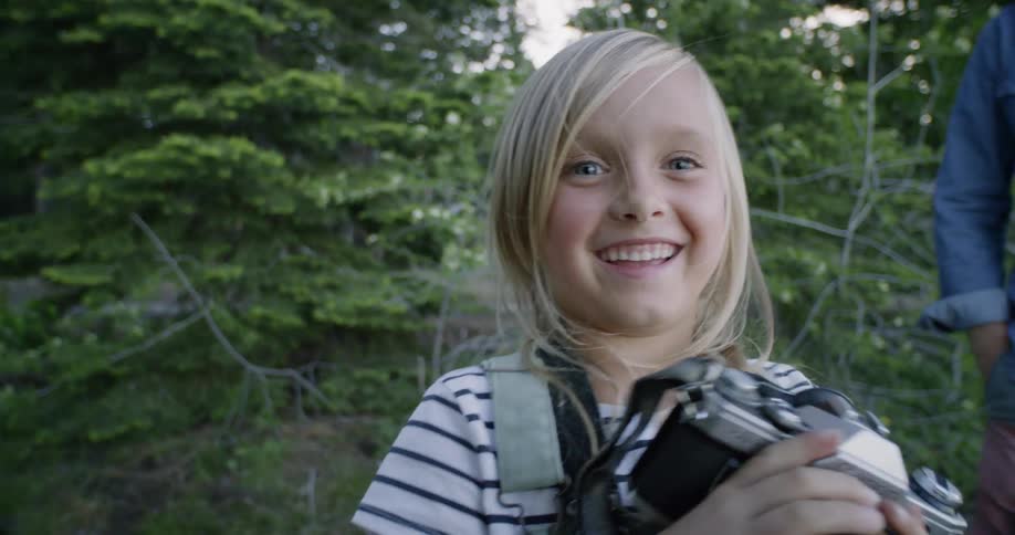 Little girl smiling after looking through viewfinder on camera outside