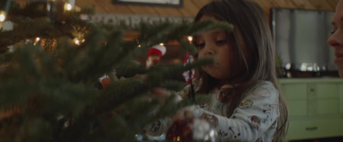 A young girl helps decorate a christmas tree