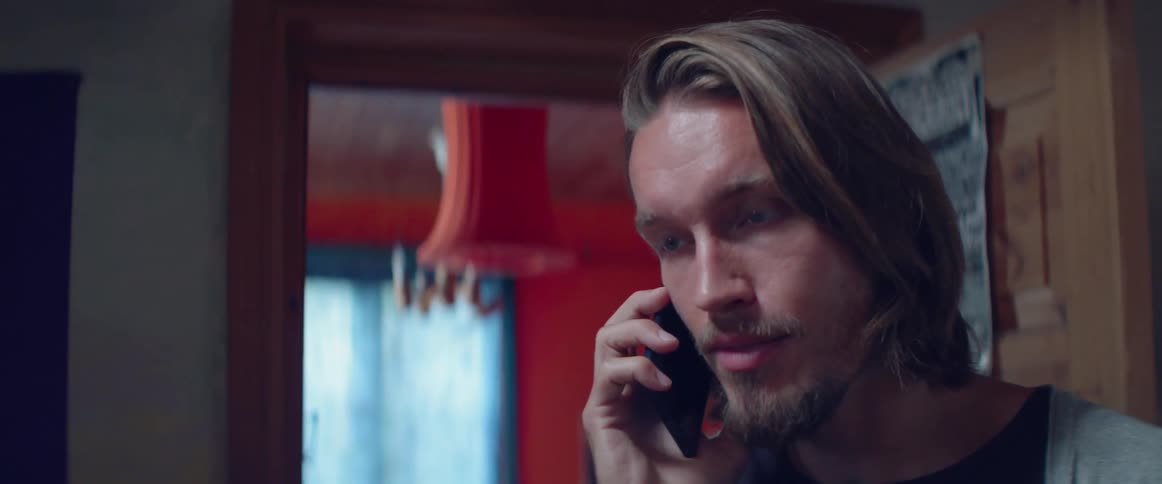 A focused guy lowers his gaze slightly during a serious smartphone call home.