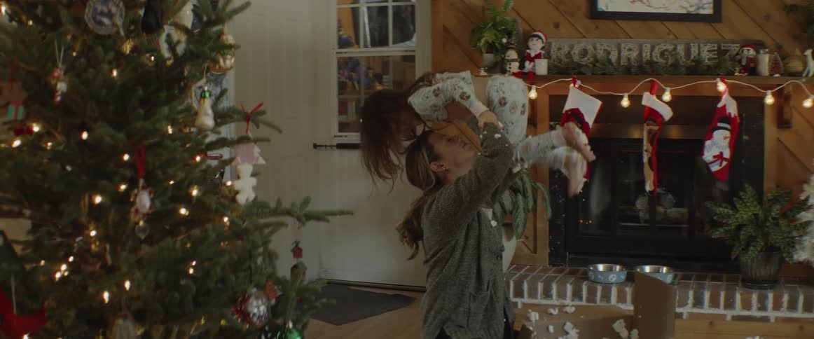 A woman plays with a young girl by the christmas tree