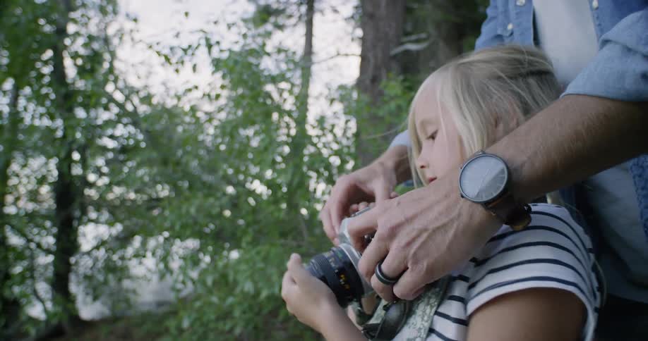 Man helps girl take a picture in the woods