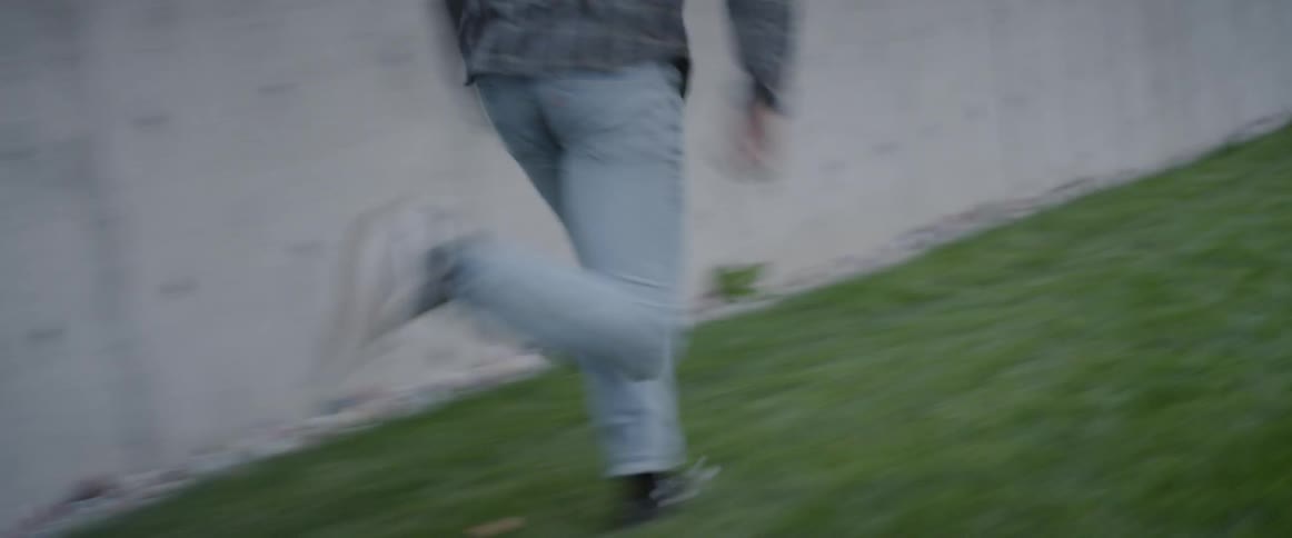 A man is leaping over a wall and running from a dog in daylight
