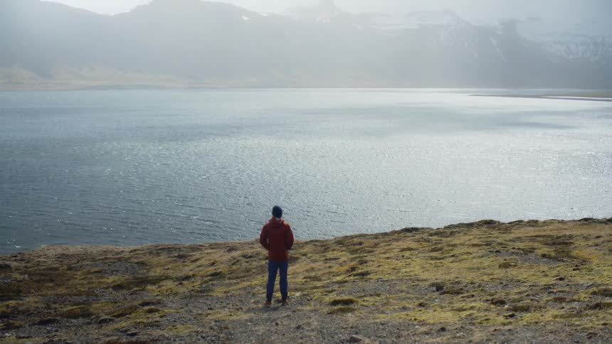 Person stands on the banks of a wide river
