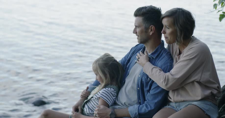 A family sits near a body of flowing water
