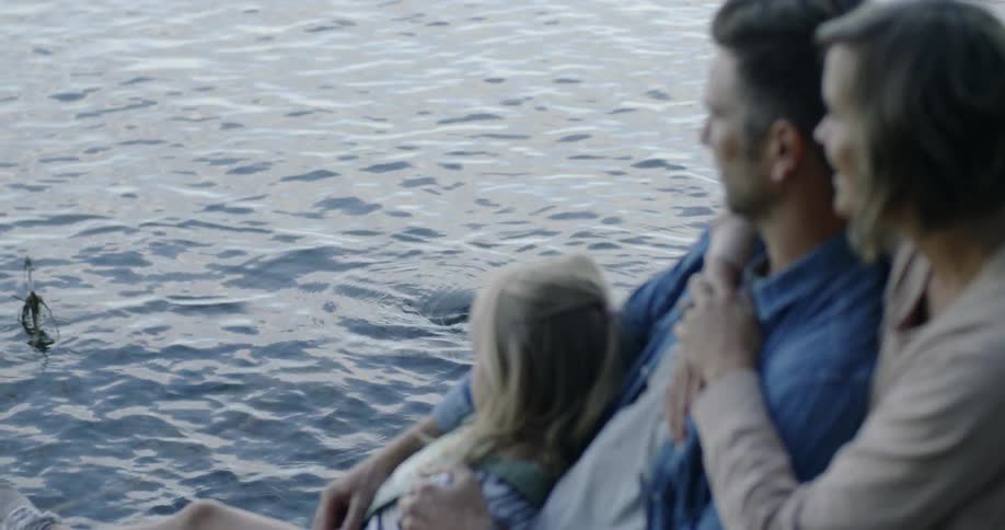 Family relaxing next to rippling water in lake