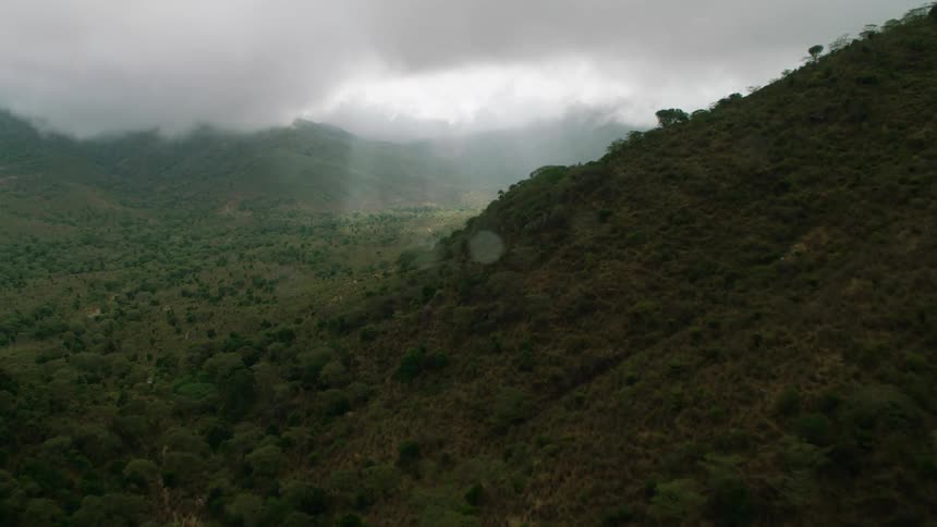 Sun shines through the clouds onto hilltops and valley