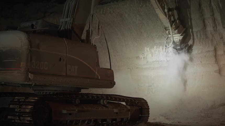 Mining equipment grinds away at a rock wall