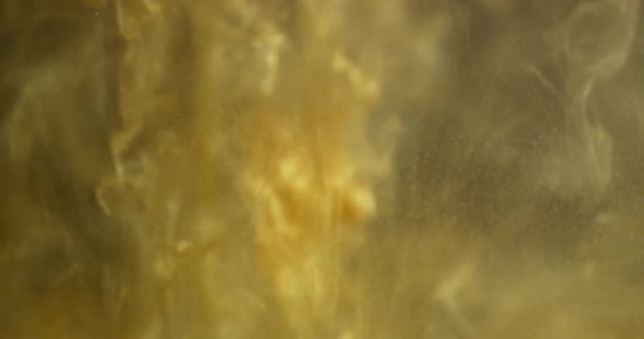 Golden colored liquid pours down into clear liquid