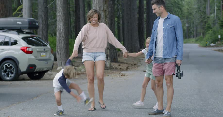 Parents hold hands with their children on a forest road