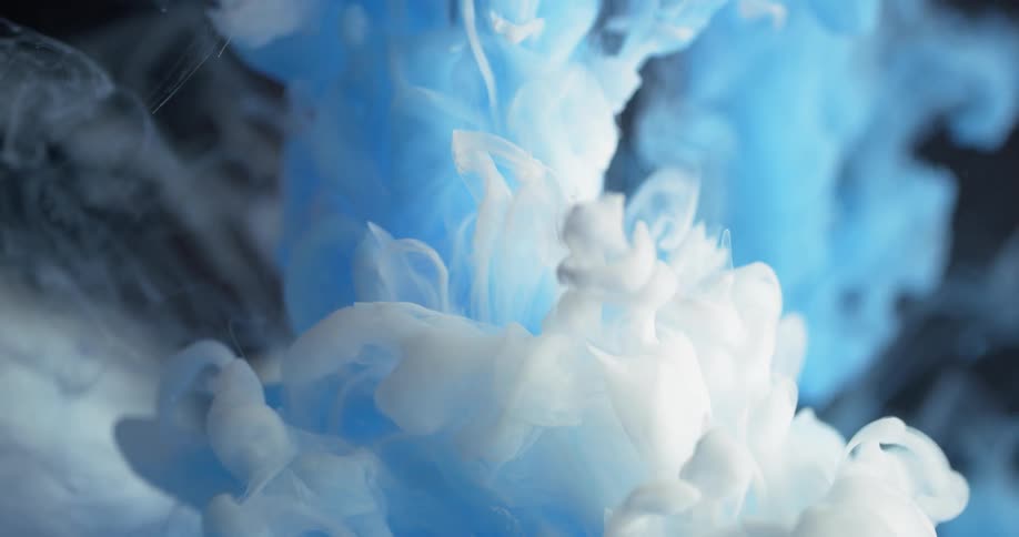White and blue dyes are pouring into and spreading out in a liquid solution