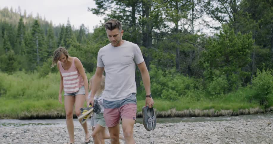 Family walks on rocks near a small stream