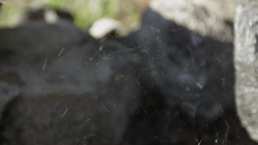 Spider web waves in the sunlight near large rocks