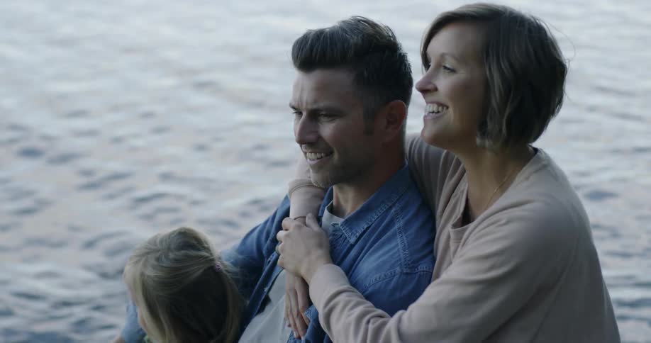A family sits next to a lake at sunset