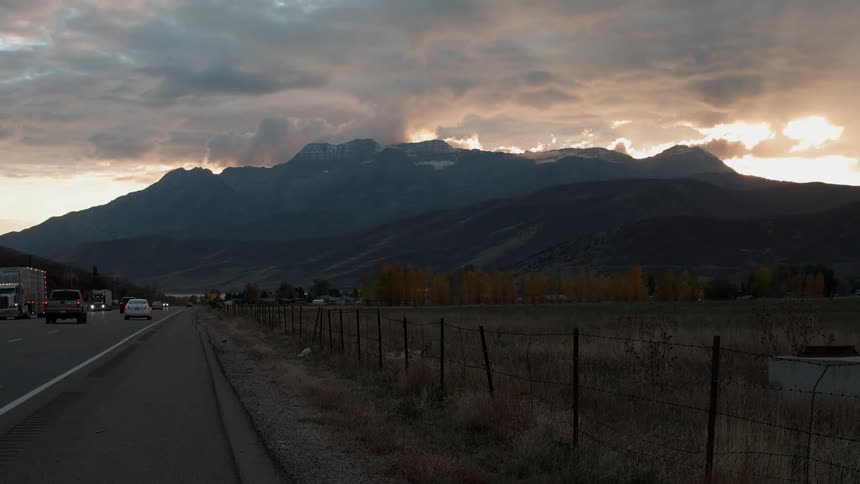 Cars and trucks traveling on mountain highway on cloudy evening