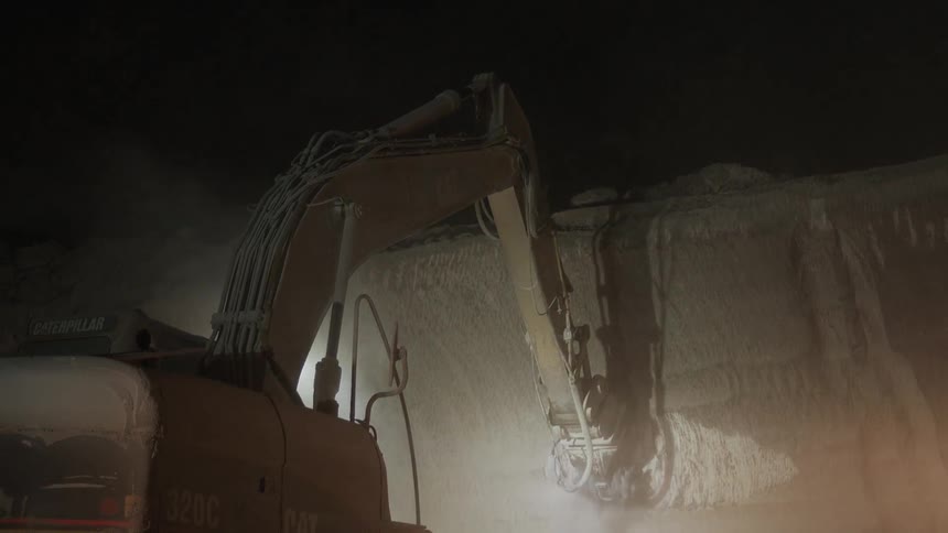 Machine drills at a stone wall at night