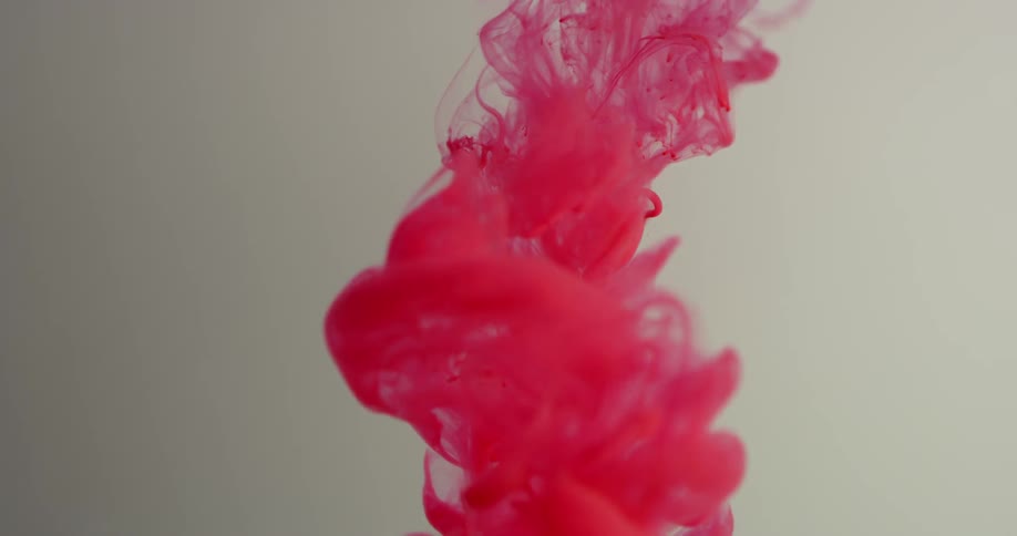 Red dye is falling into and spreading out in a liquid solution