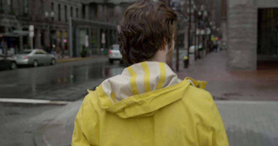 A man crosses a busy street while it rains