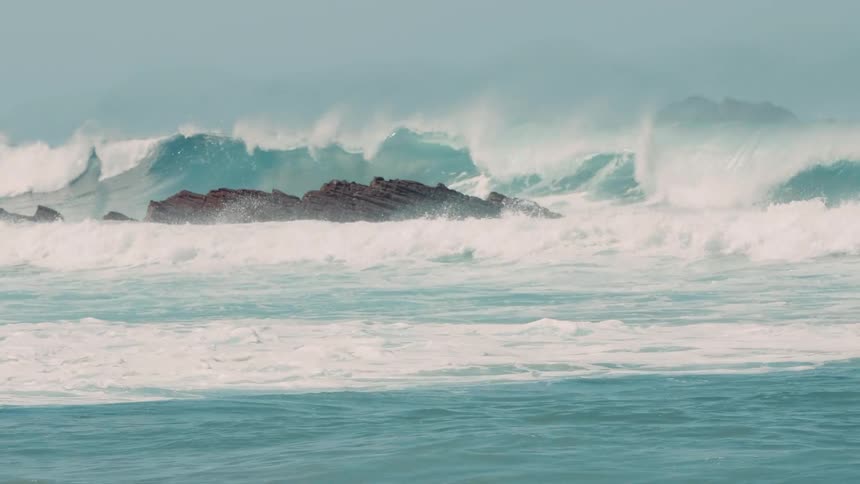 Large waves are crashing onto rocks in the ocean