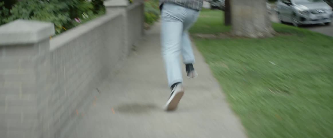 Man turns down sidewalk and runs as fast as he can in neighborhood