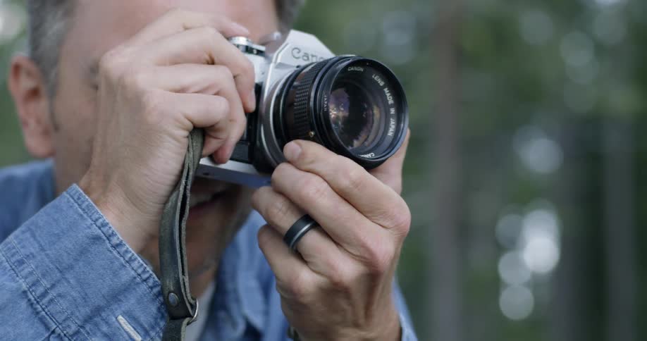 A man adjusts the focus of a camera outside
