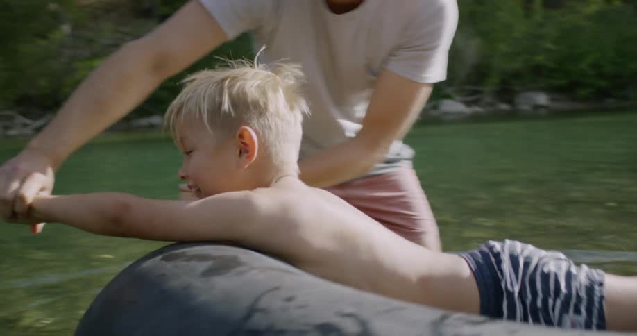 A man pulls his son on a tube in the river