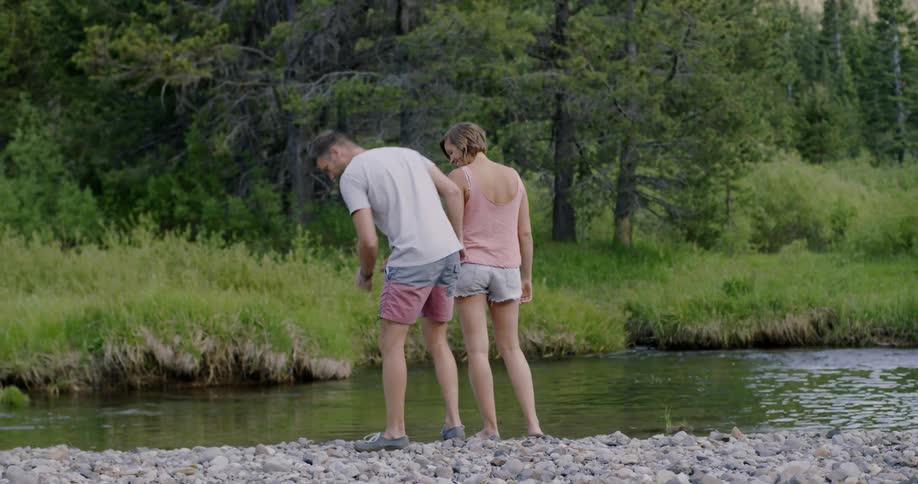 Man and woman look for rocks next to river