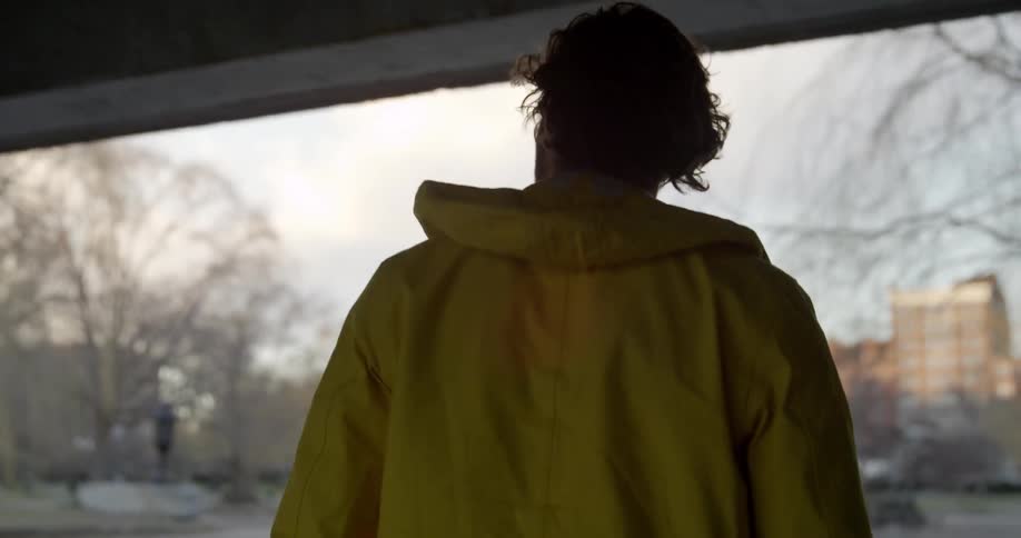 Man walks under an overpass and looks up to the sky