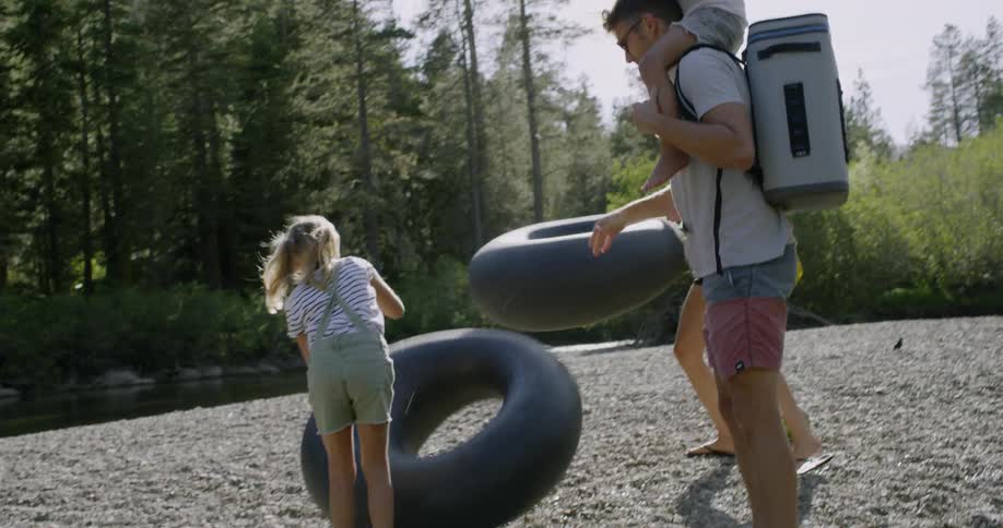 A family carry rafts to the side of a river