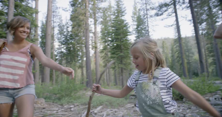 Mother hands daughter a stick out in nature