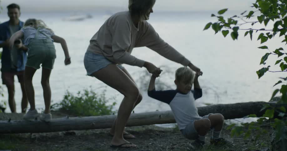 Mother and father play with their children next to lake