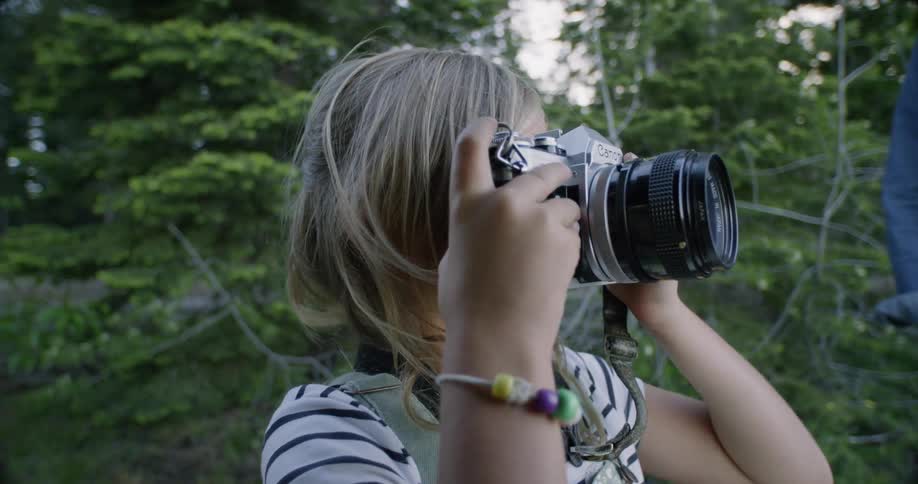 Little girl looking through viewfinder of camera outside