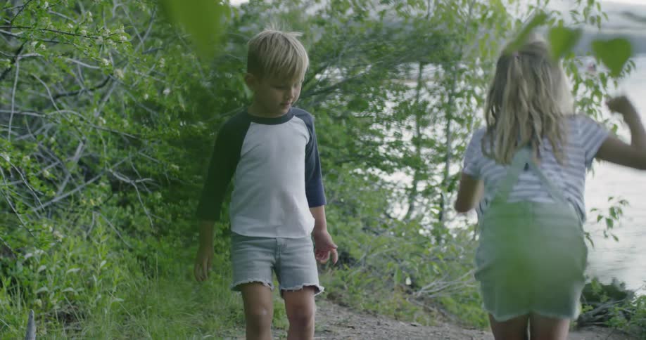 Girl and boy jump and play outside next to lake