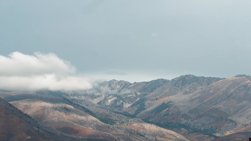 Clouds are casting shadows on a mountain landscape during the day