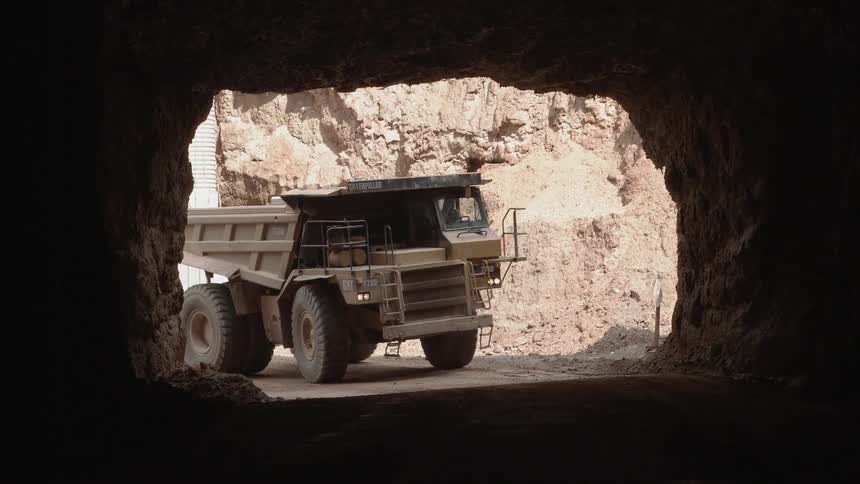 Large dump truck driving into a tunnel on a bright day