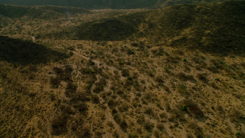 The green hills have a trail running through