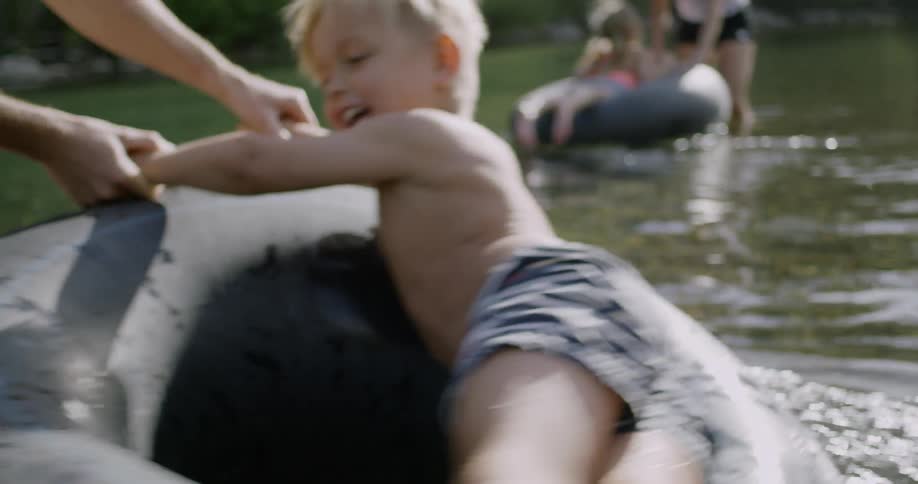 Father twirling son around on inner tube in river water