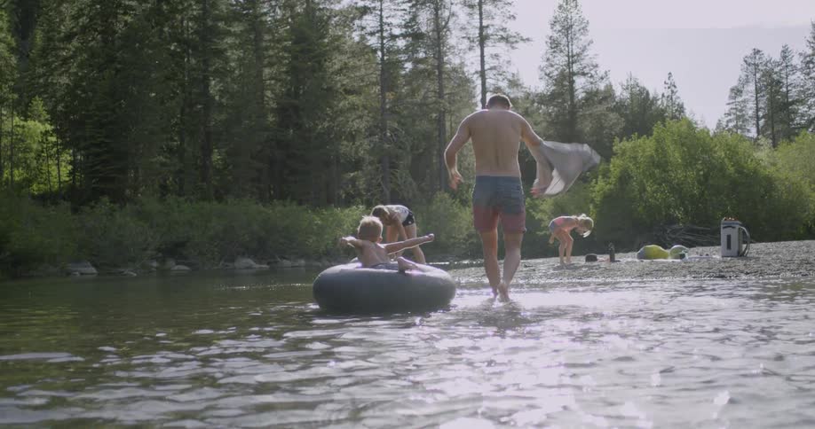 A family are playing in a lake in a natural setting on a sunny day