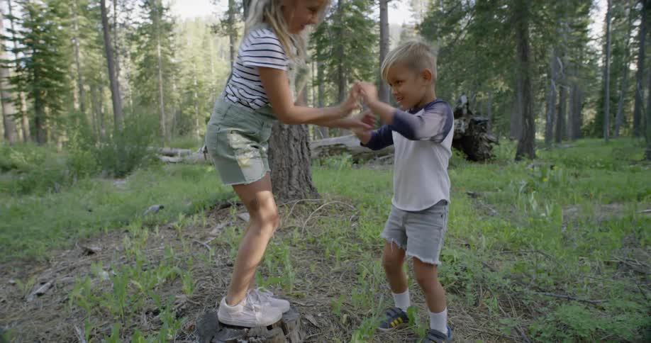 Little boy and girl are play fighting in a wooded area