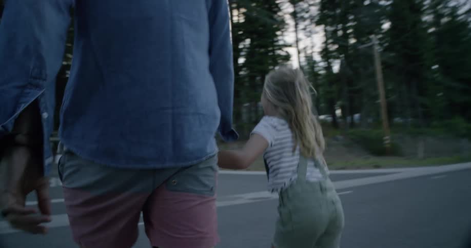 Woman holds a girls hand as they walk across a street in the country