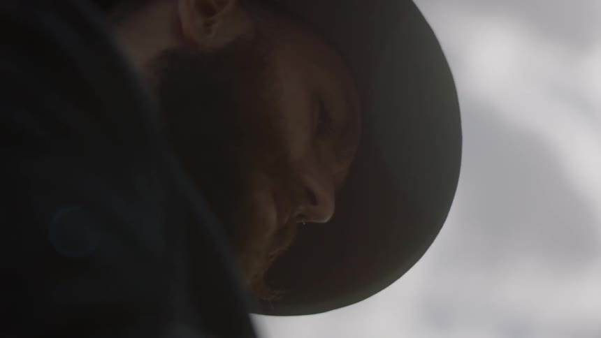 Man wearing a hat looks down