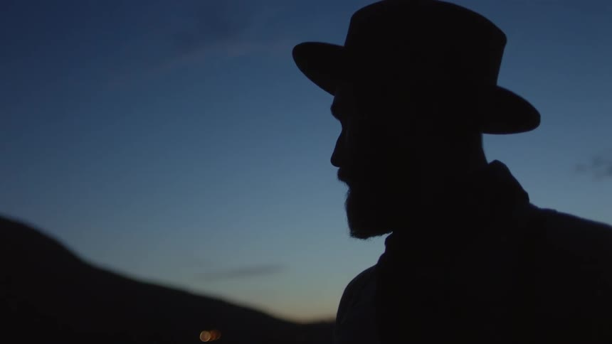 A man in the shadow of the sunset looks ahead