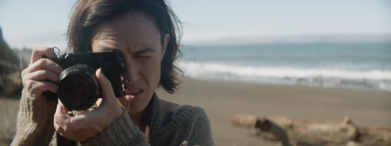 A woman takes photographs on a beach
