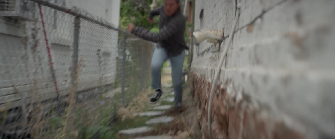 Man sprints down an alleyway between two houses