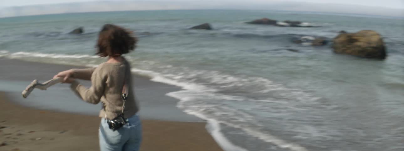 Woman throws a stone in the air and hits it with a stick into the ocean
