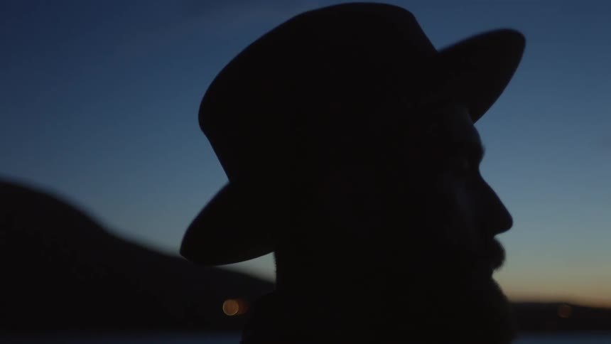 Man wearing hat is outside at dusk