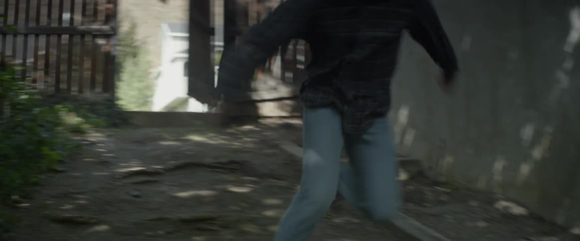 A man burst through a gate and runs in the backyard