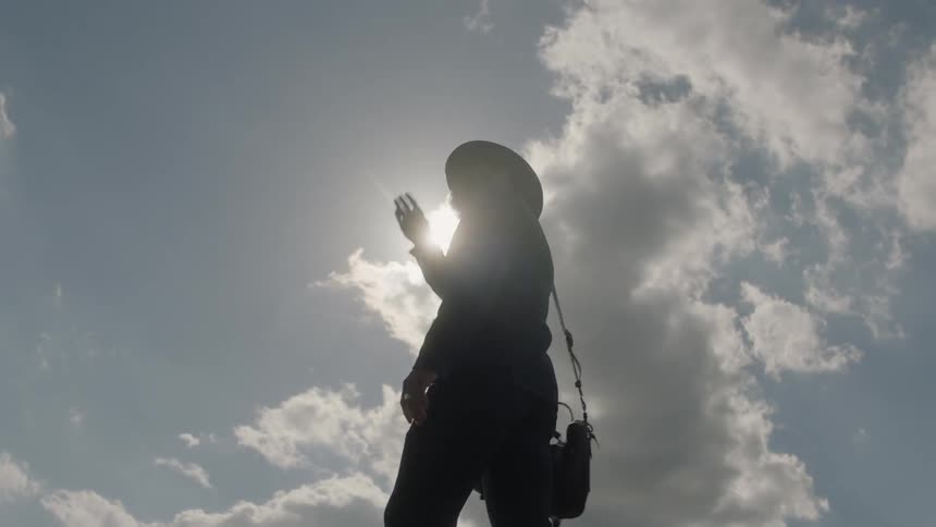 A man standing outside in sunlight is shielding his eyes